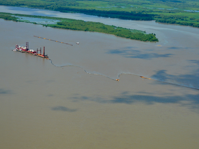 Behind the dredge California, the river island at Horseshoe Bend on the lower Atchafalaya River, Louisiana is being self-designed by dredged sediment strategically placed upriver (lower right), allowing the river's energy to disperse the sediment. The dispersed sediment contributes to the island's growth, thus creating environmental and other benefits. (Photography by Wings of Anglers, courtesy of Great Lakes Dredge and Dock)